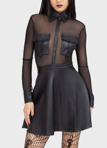 Woman wearing a black outfit with sheer top and skirt on a white background